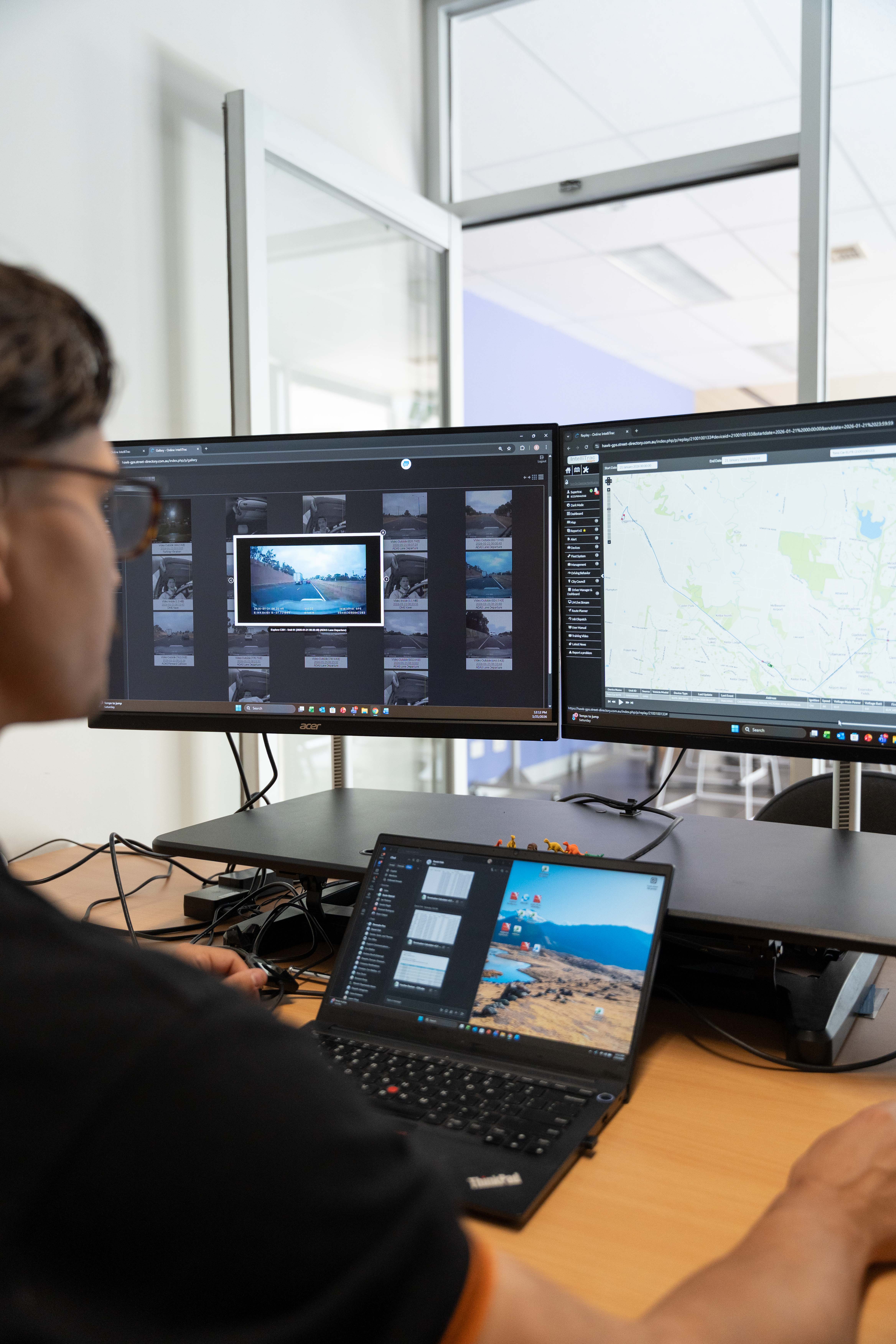 Operator monitoring IntelliTrac telematics, live video and dashcam footage on desktop screens.